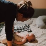 woman in black long sleeve shirt holding baby in white onesie